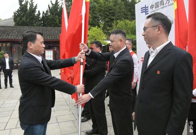 安顺供电局党委副书记、总经理幸兆森（右）将党旗交到下属党组织书记手中，倡议大家要当好“学传颂”主题活动的模范。
